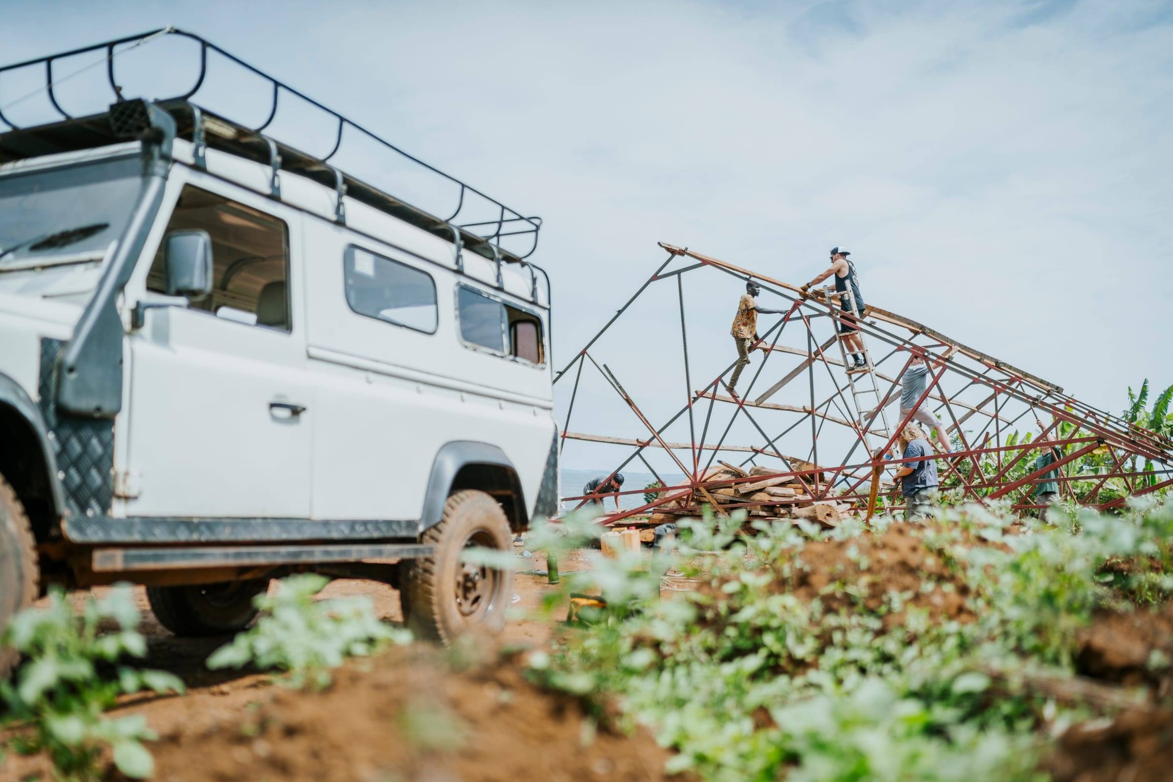 A white truck parked on a farm track beside a fallen metal tower