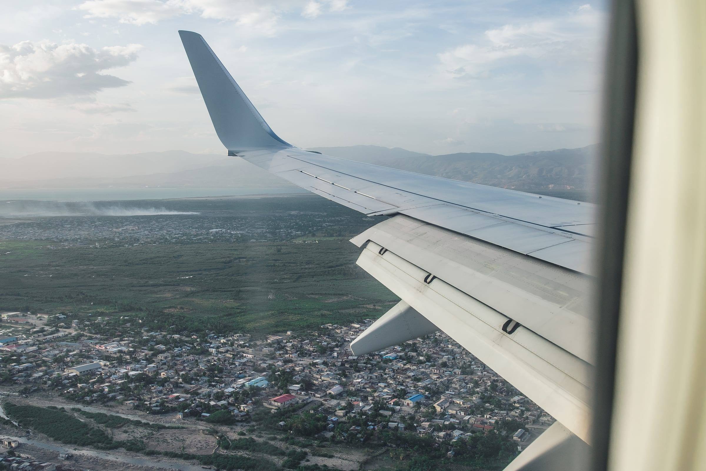 The wing of a plane above a city far below