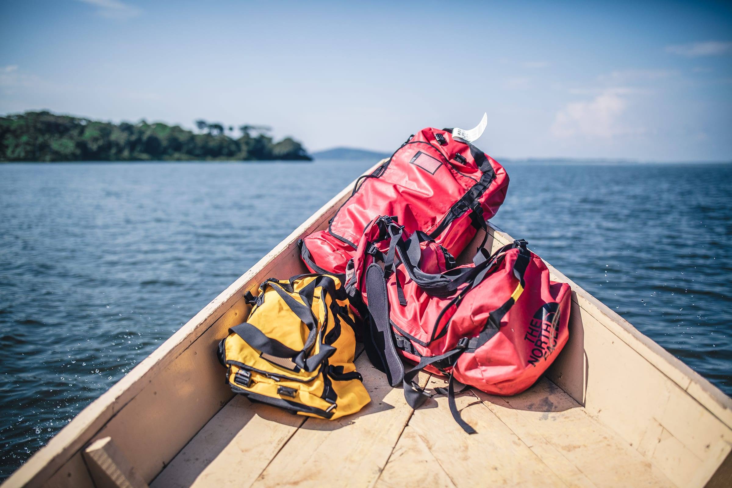 Red and yellow duffel bags in the bow of a wooden boat on open water